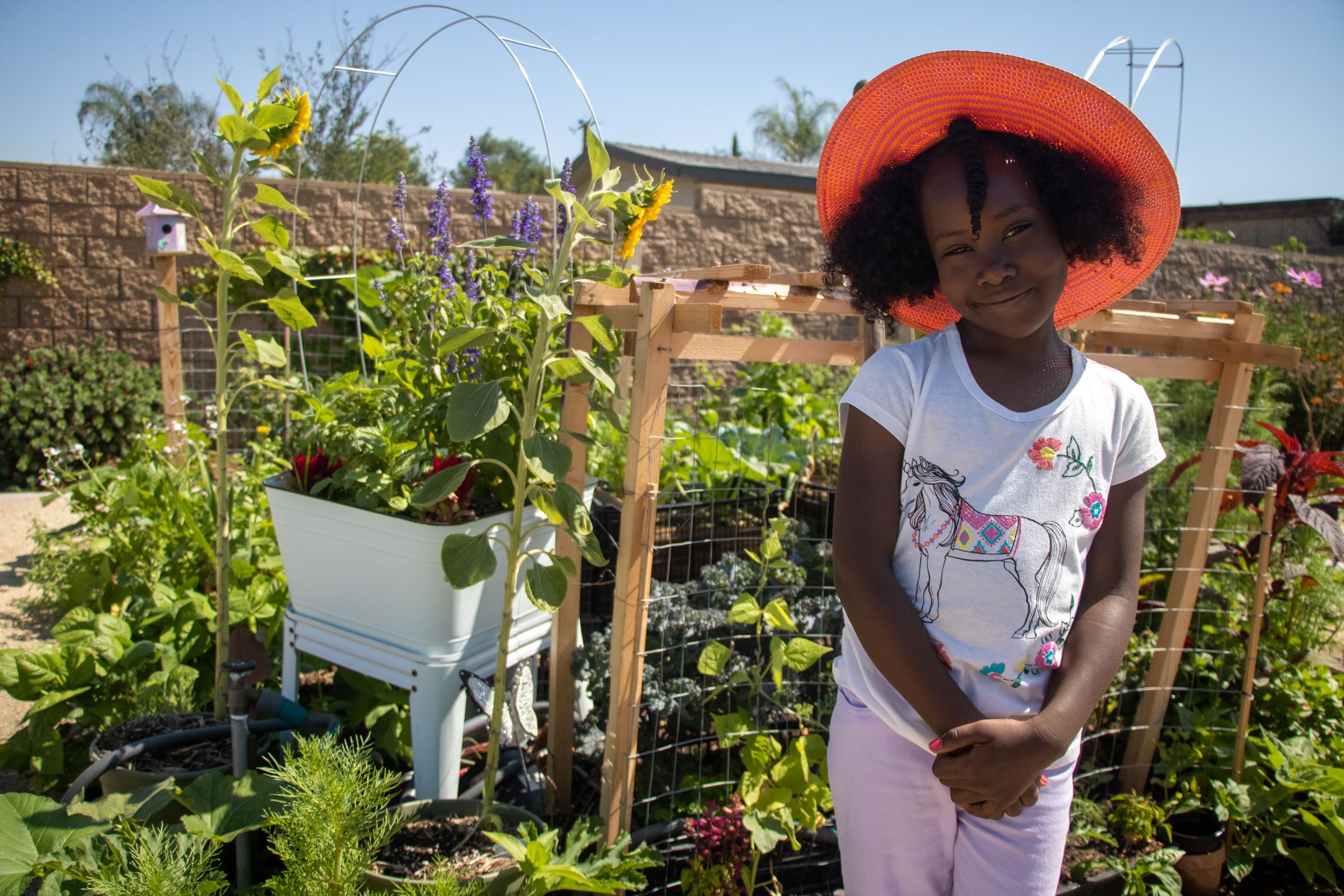 Young girl smiling in front of a garden. 